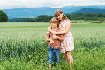 Two adorable kids playing together in summer wheat field