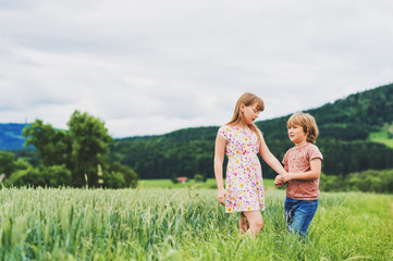Two adorable kids playing together in summer wheat field