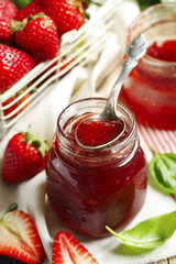 Homemade strawberry jam with basil in a glass jar and fresh strawberries on table