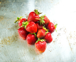 Fresh strawberries heap on shiny metal background, top view