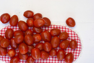 Cherry plum snack tomatoes on a white wooden background. Closeup and top view.
