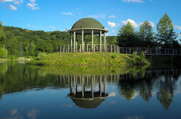 Obraz premium Arbor on the lake in the park against the blue sky