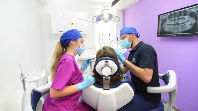 Young dentist and assistant treating a pacient at dental clinic