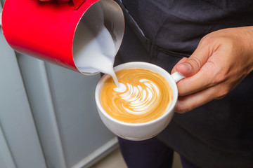 Barista holding cup latte art coffee in cafe.