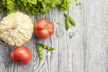 Red tomatoes, white pumpkin, green peas and salad on wooden table
