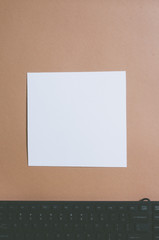 Top view of keyboard on creamy brown colored background with white frame as copy space