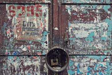 Old wooden door with a lock glued scraps of stickers.
