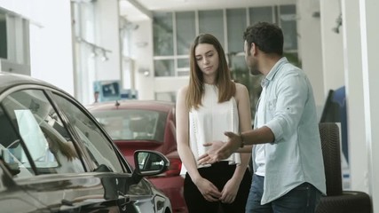 Young couple arguing and choose the car in car dealership