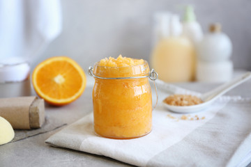 Glass jar with orange body scrub on napkin