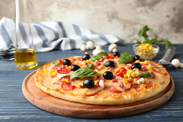 Tasty pizza and its ingredients on wooden table