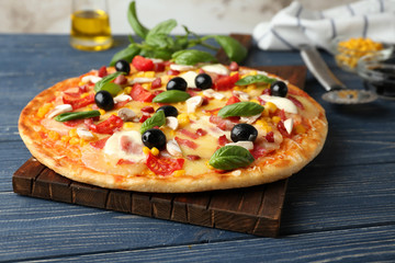 Tasty pizza and its ingredients on wooden table