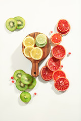 Wooden board with citrus slices on white background