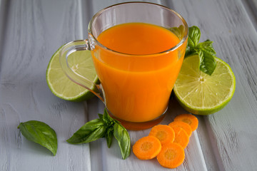 Carrot juice in the glass cup on the grey background