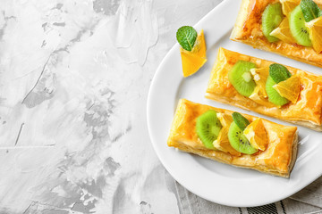 Plate with delicious puff pastry dessert and fruits on light background