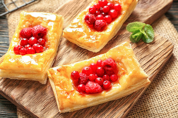 Tasty puff pastry dessert with berries and honey on wooden board