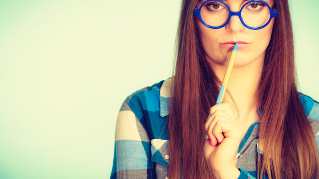 Nerdy thinking woman in glasses holding pen