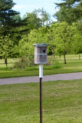 The round wooden birdhouse in the grass.
