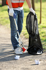 Young volunteer picking up litter in park
