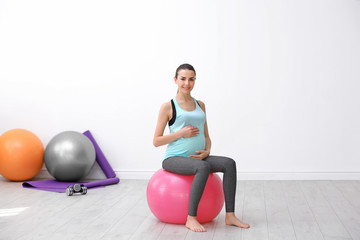 Obraz premium Beautiful pregnant woman doing exercise indoors