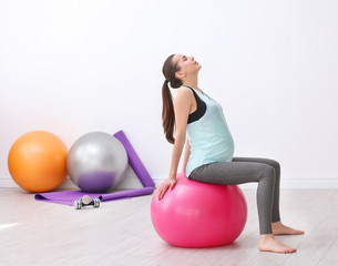 Beautiful pregnant woman doing exercise indoors