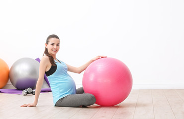 Fototapeta na wymiar Beautiful pregnant woman doing exercise indoors