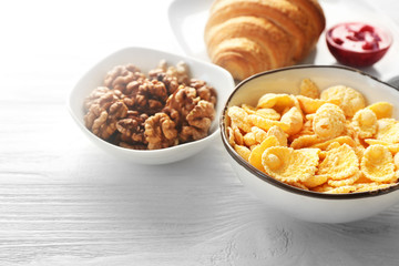 Tasty breakfast with corn flakes in bowl on white table