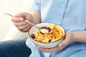 Human hands holding bowl with corn flakes and berries for breakfast
