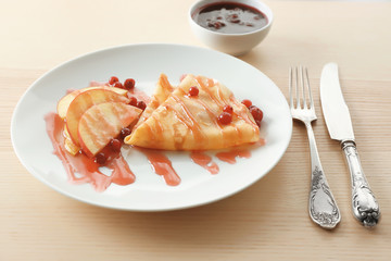 Tasty crepe with berry sauce for breakfast on table