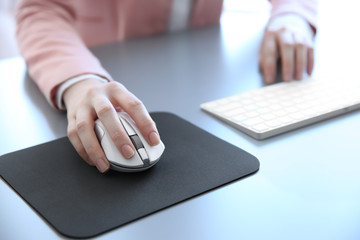 Female hand holding computer mouse on pad