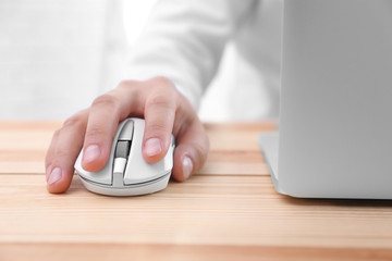 Male hand with computer mouse and laptop on table