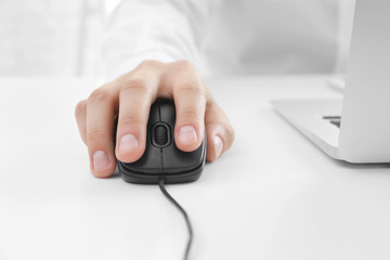 Male hand with computer mouse on table