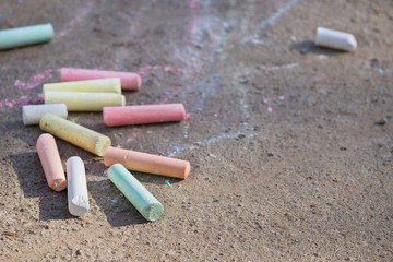 Colorful chalk lying on asphalt. Bright street chalks on pavement, top view