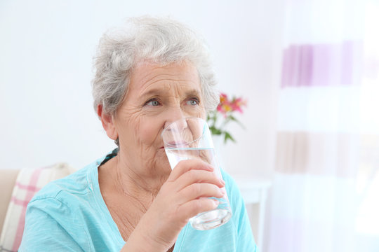 Elderly woman drinking water at home. Concept of retirement