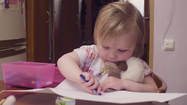 Little baby girl drawing at a table