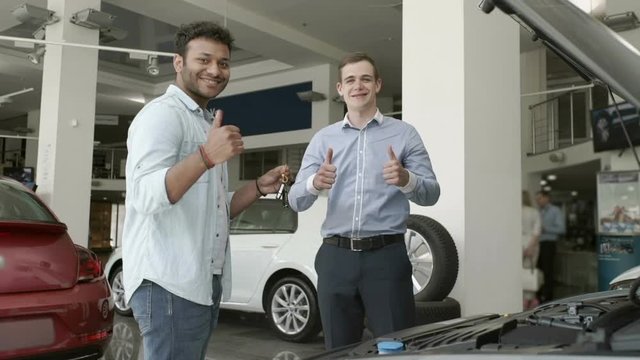 The salesman give the keys to a buyer in car showroom