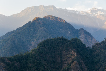 Naklejka premium Green hill near Kangchenjunga mountain with clouds above and trees with sunlight that view in the evening in North Sikkim, India.