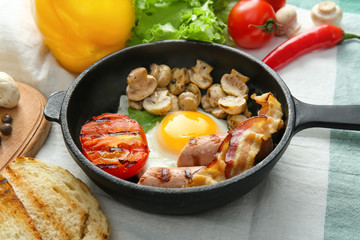 Frying pan with tasty egg, bacon and mushrooms on table