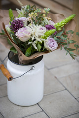 Closeup of white metal bucket full of beautiful flowers. Flowers in vase on concrete background. Summer or spring. Outdoor