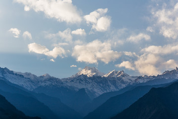 Kangchenjunga mountain with clouds above. Among green hills and trees that view in the evening in North Sikkim, India.