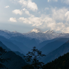 Kangchenjunga mountain with clouds above. Among green hills and trees that view in the evening in North Sikkim, India.
