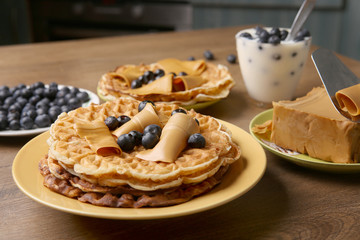 Heart shaped pancakes with brown caramel cheese and blackberries. Sweet lunch: yogurt with blackberries and pancakes on wooden table in kitchen.