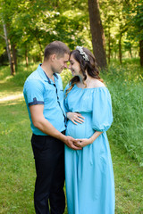 Pregnant couple. Husband touching his wife belly in nature