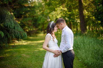 Happy and young pregnant couple hugging in nature