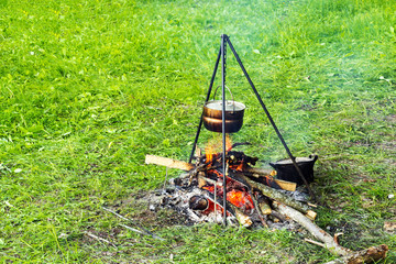 Bowler on a tripod over a fire, cooking food in a field tent camp