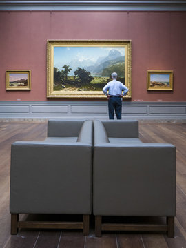 Man Examining Painting In Art Museum