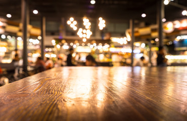 Fototapeta na wymiar Empty wood table top on blur light gold bokeh of cafe restaurant in dark background/selective focus.