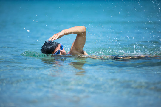 Young man swimming the front crawl in the sea (swimmer, triathlon)
