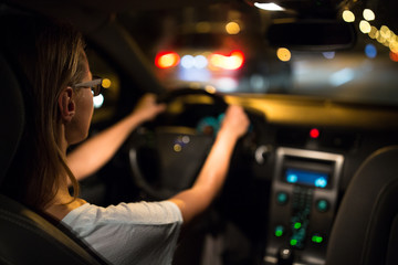 Fototapeta na wymiar Female drive driving a car at night (shallow DOF; colour toned image)