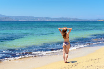 Fototapeta na wymiar Beautiful young and happy woman having a good time on a summer beach. Agia Anna beach. Naxos, Cyclades Islands, Greece.