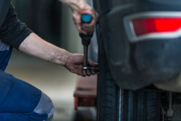 Obraz premium Inside a garage - modern car waiting for the mechanic to change its wheels/tires (shallow DOF; color toned image)